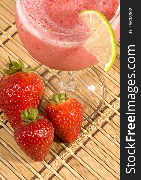A fruit smoothie with a lime garnish and strawberries. A fruit smoothie with a lime garnish and strawberries.