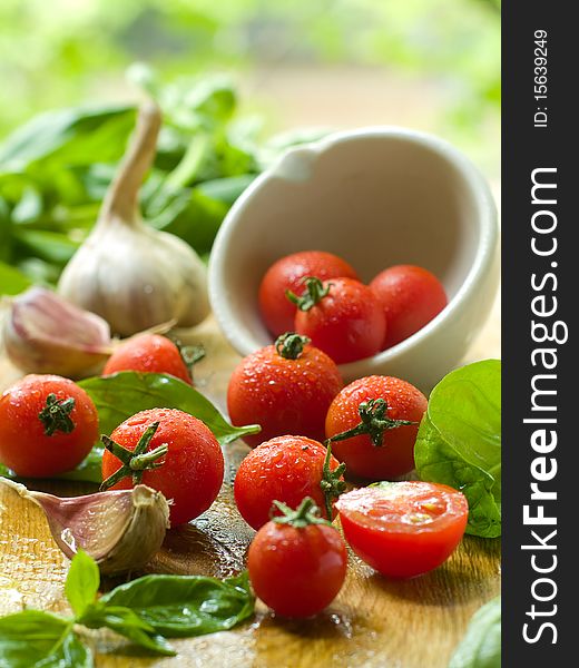 Cherry tomatoes on table and in a bowl with basil and garlic