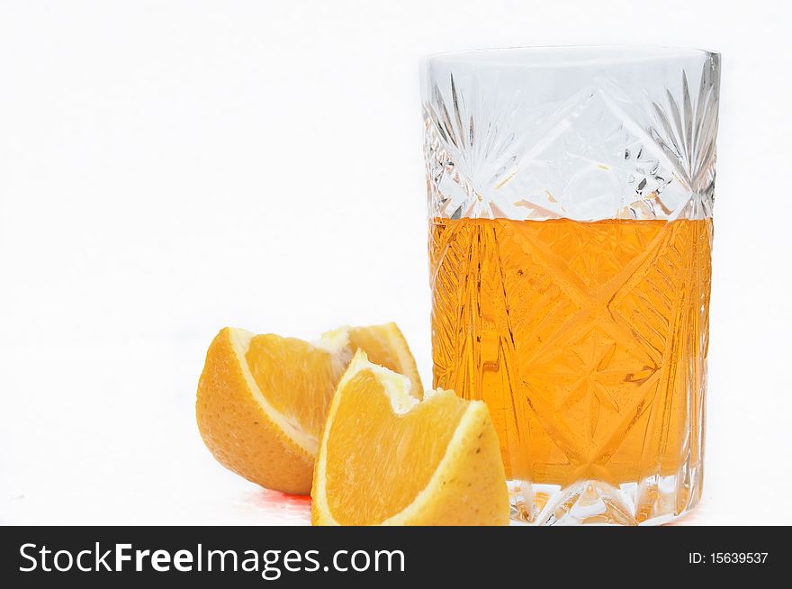 Crystal glass of orange juice and two segments of an orange. Isolation. Crystal glass of orange juice and two segments of an orange. Isolation