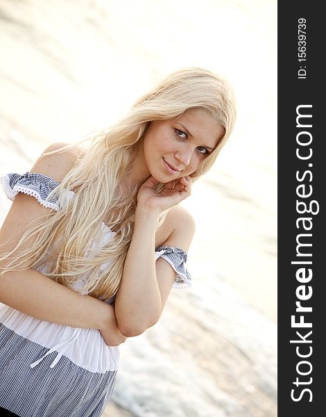 Beautiful young blonde girl on the beach of Black Sea. Sea and sunlight is on background.