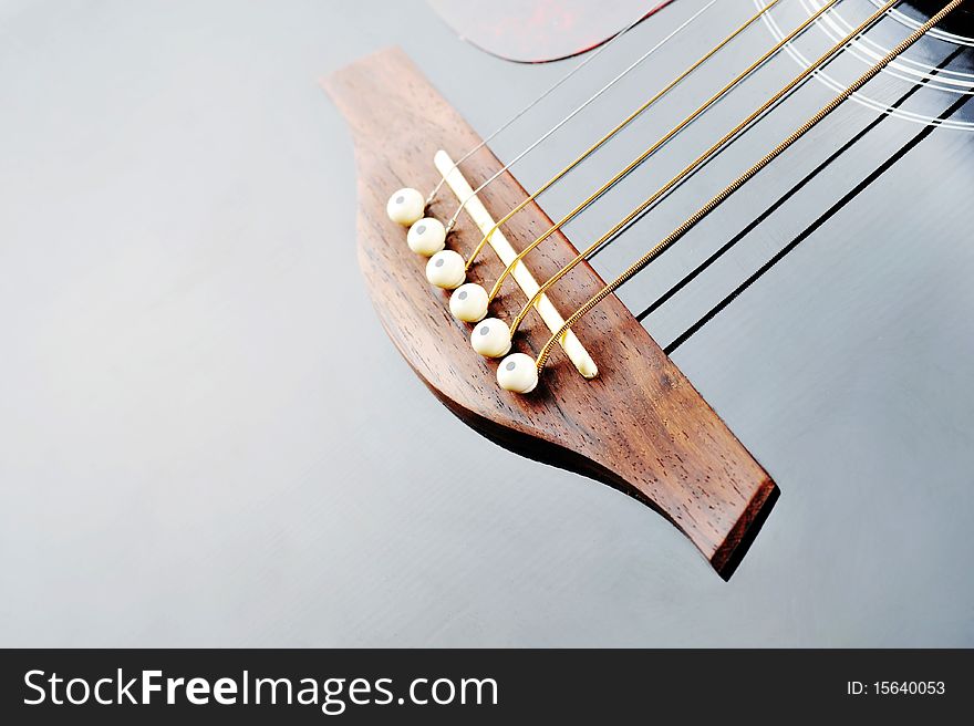 Detail of an acoustic black guitar with the strings