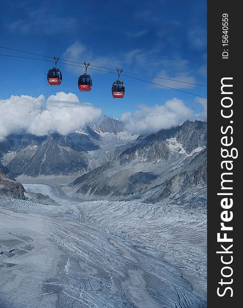 Three red cablecars gliding above the Glacier Blanche near Chamonix and the Aiguille du Midi.