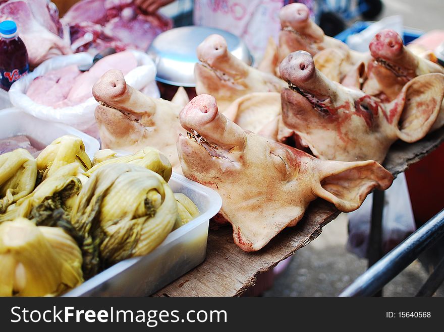 A lot of pig head in the market with green cabbage on sell