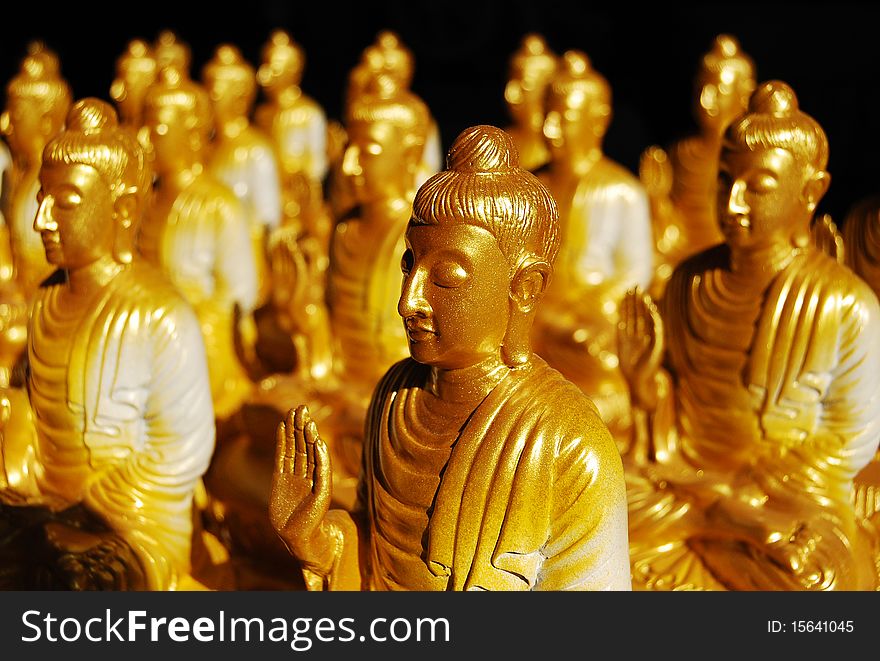 A lot of Golden buddha statue arrange orderly with dark background. A lot of Golden buddha statue arrange orderly with dark background