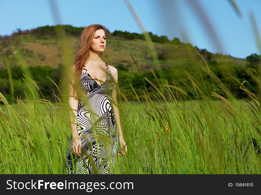 Young beautiful woman standing on the green field. Young beautiful woman standing on the green field