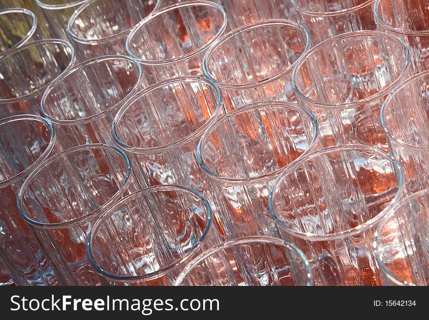 Many empty, transparent glass cup standing on an orange background. View from above. Many empty, transparent glass cup standing on an orange background. View from above.