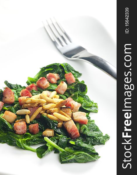 Fried spinach with bacon and pine nuts