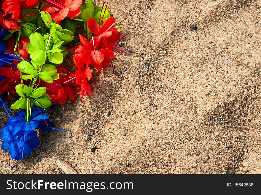 Artificial colorful wreath on the sand. After party.