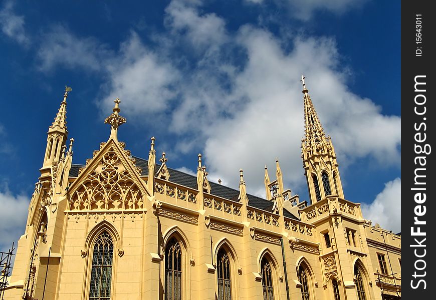 Yellow colored neo-gothic church with spires under blue sky, Lednice, Czech republic