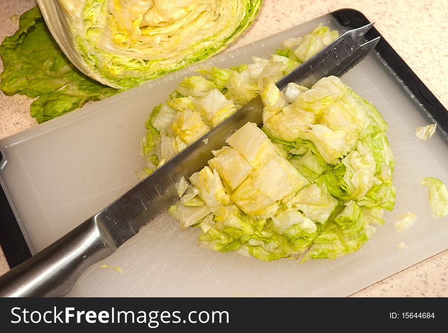 A cutup head of iceberg lettuce with a knife laying through it. A cutup head of iceberg lettuce with a knife laying through it