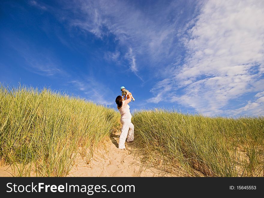 Mother with the baby on hands on the sandy sand dune