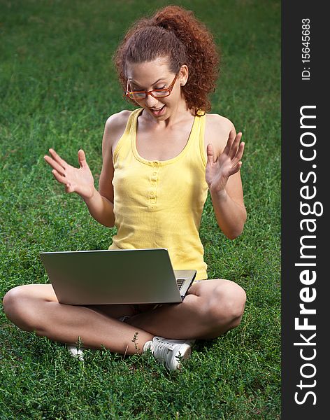 Young Woman with laptop on a meadow rejoices success