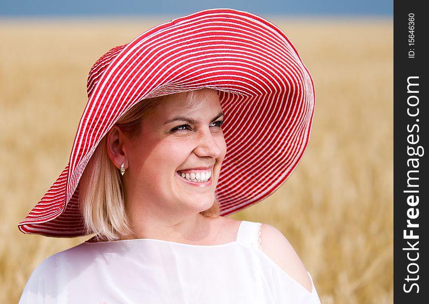 Beautiful woman with hat in wheat meadow on sunny day