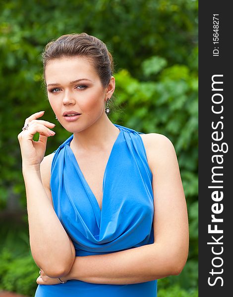 Outdoors portrait of pretty young adult in blue dress. Outdoors portrait of pretty young adult in blue dress