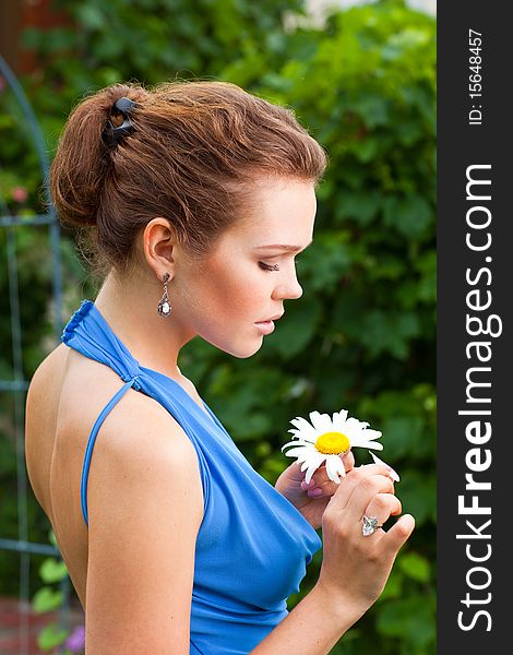 Attractive young adult holding camomile and tearing off petals. Attractive young adult holding camomile and tearing off petals