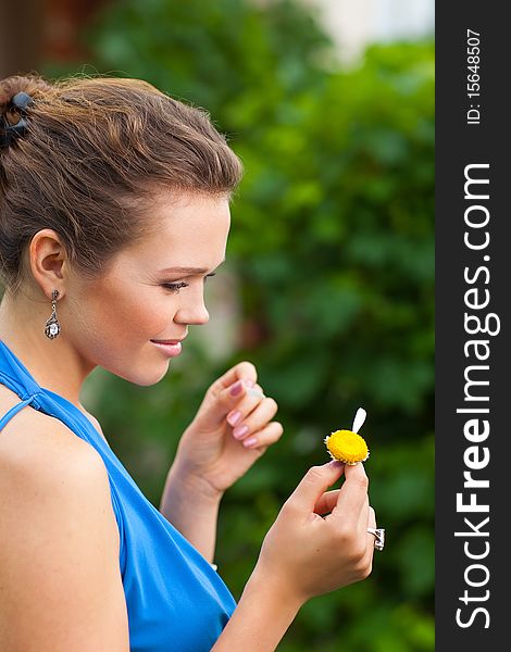 Attractive young adult holding camomile and tearing off petals. Attractive young adult holding camomile and tearing off petals