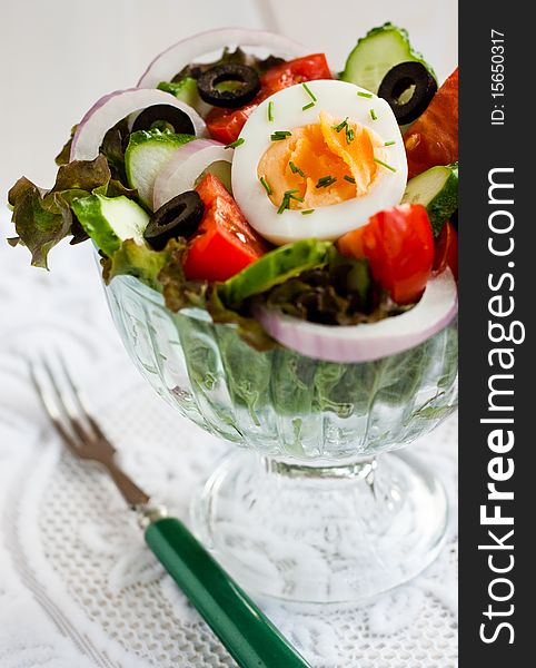 Vegetable salad with an egg on a white lacy napkin