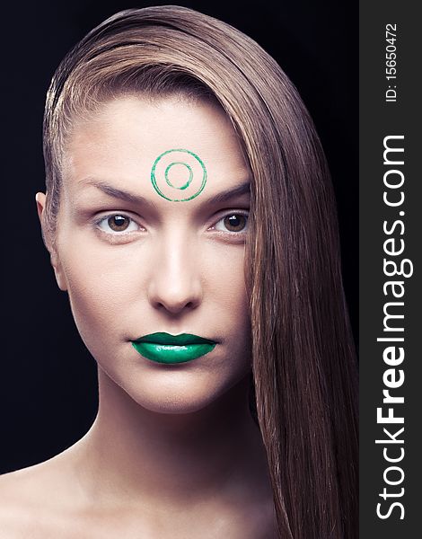 Art make-up on the person young, beautiful, girls. The girl with a make-up of green lips and green circles on a forehead