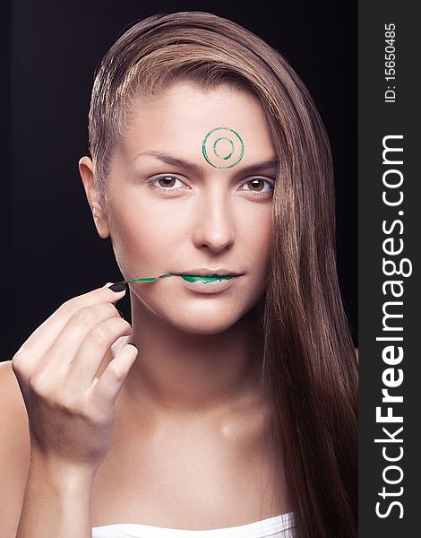 Art make-up on the person young, beautiful, girls. The girl with a make-up of green lips and green circles on a forehead