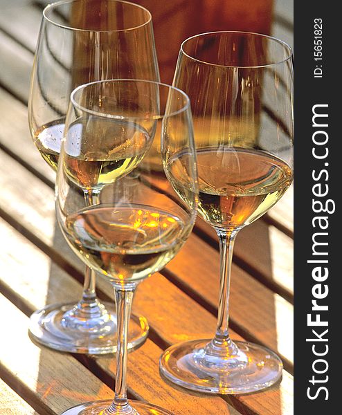 Glasses of white wine with a bottle on a wooden table