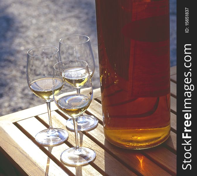 Glasses of white wine with a bottle on a wooden table