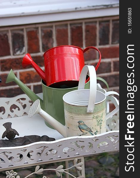 Three watering cans on the shelf