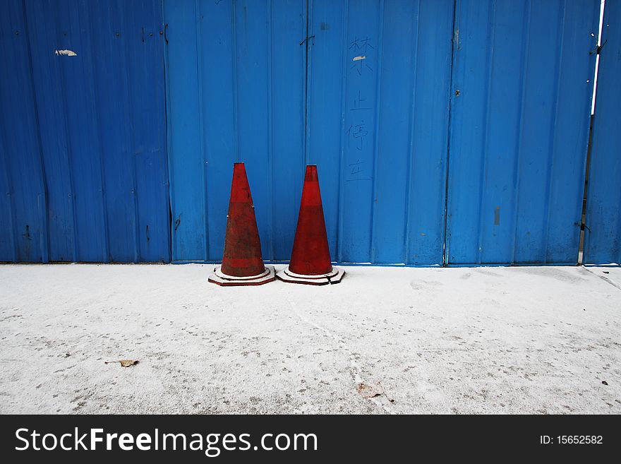 Traffic cone in front of a blue wall