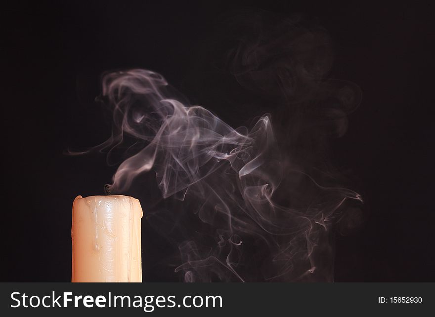 Extinguished  candle with smoke on black background with copy space