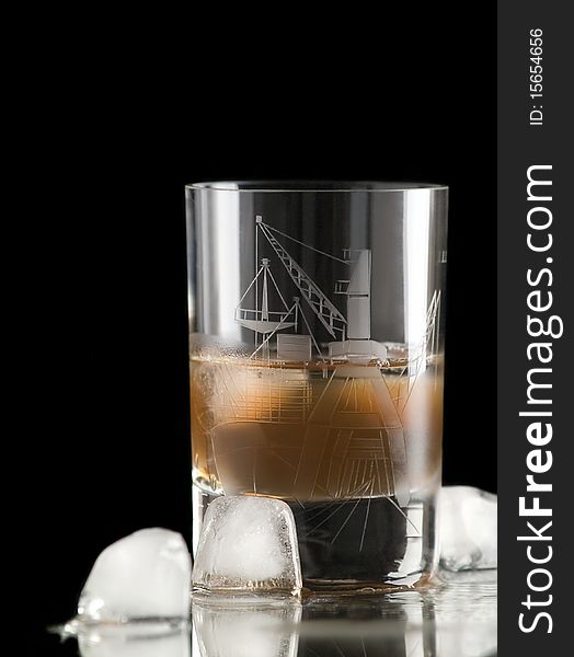 The photo shows a glass filled with whiskey and some ice cubes