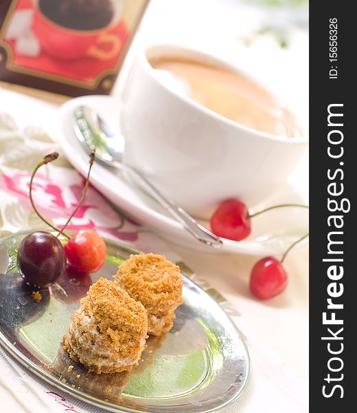 Two small honey cakes on a plate with cherry and coffee in background. Two small honey cakes on a plate with cherry and coffee in background.