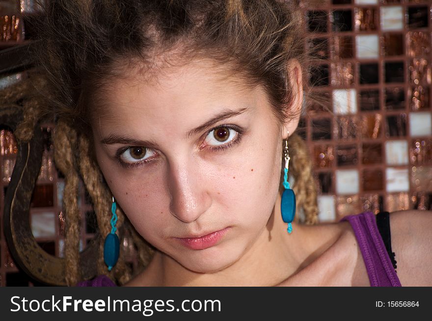 Portrait of a young girl with dreadlocks on the background of a decorative mosaic. big eyes. blue earrings. Portrait of a young girl with dreadlocks on the background of a decorative mosaic. big eyes. blue earrings.