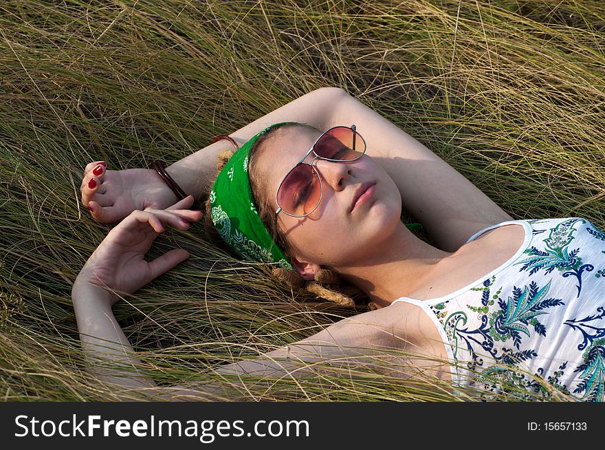 Young woman in a green headscarf and sunglasses lying on the grass. Young woman in a green headscarf and sunglasses lying on the grass