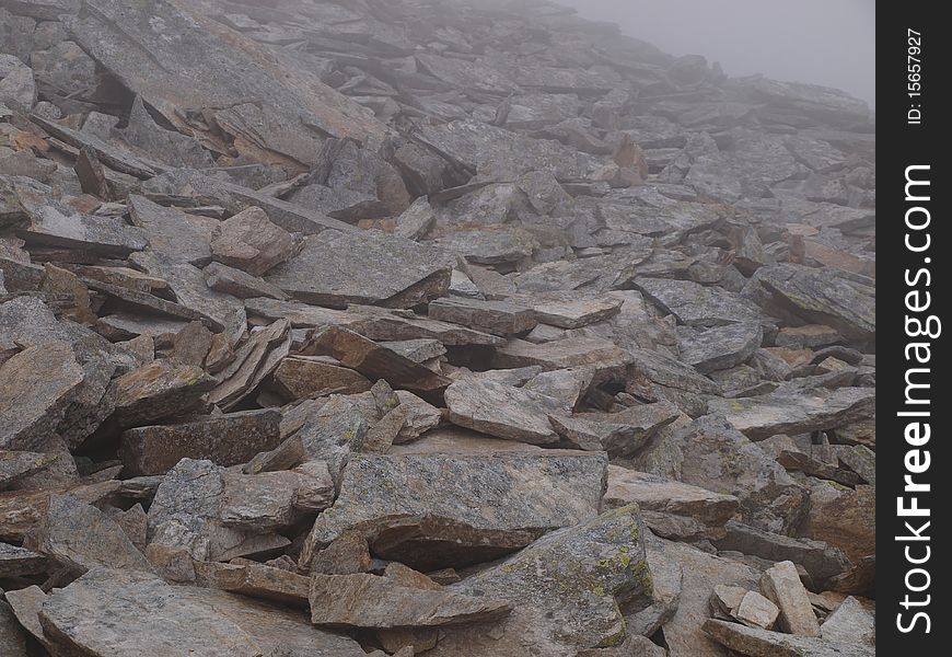 Stony, alpine, tourist trail mountain during bad weather, in fog