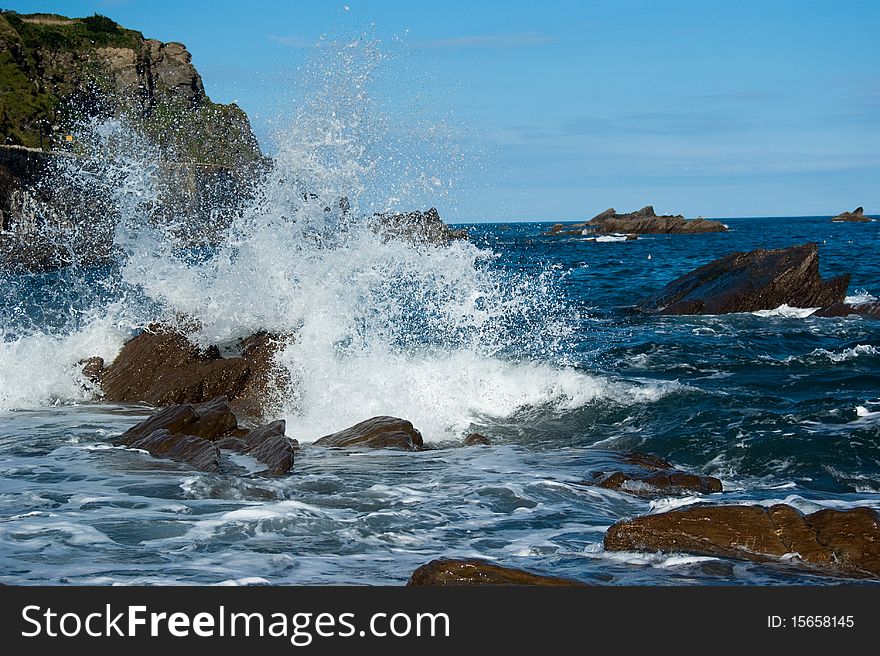 Waves breaking over rocks by the shore. Waves breaking over rocks by the shore