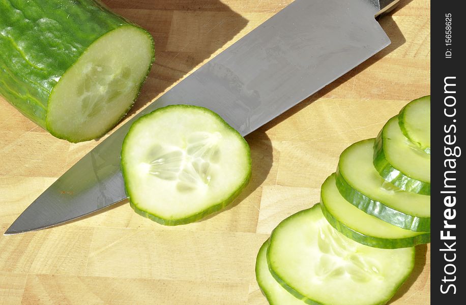 Sliced cucumber with kitchen knife on chopping board