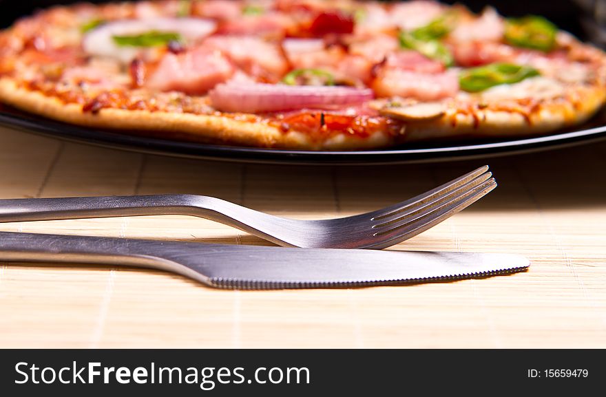 Delicious pizza with everything (focus on silverware). Delicious pizza with everything (focus on silverware)