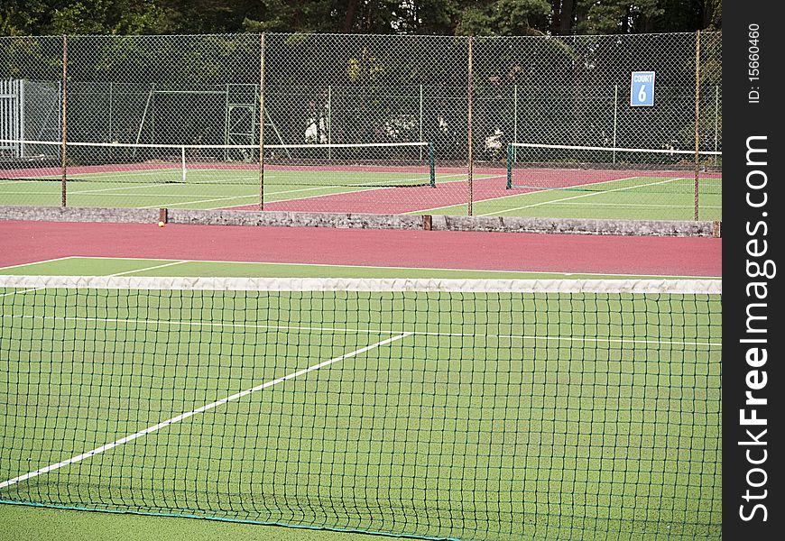 Sports center with view across 3 empty hard tennis courts painted green and red. Sports center with view across 3 empty hard tennis courts painted green and red.