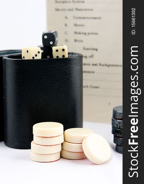 A backgammon dice and chips stacked in front of a case. A backgammon dice and chips stacked in front of a case