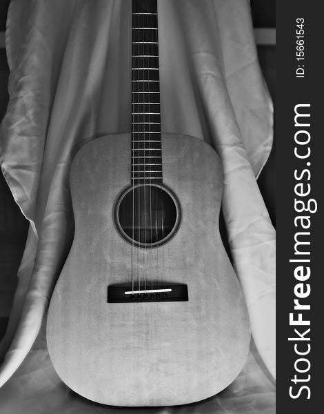 Black and White Acoustic Guitar Against a White Sheet.