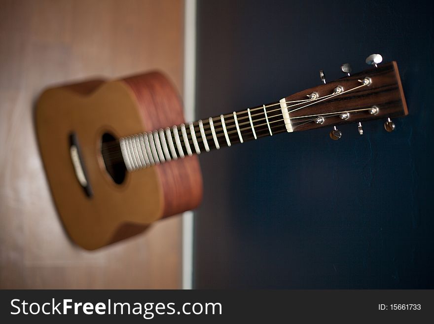 Angled view of an acoustic guitar against a blue wall. Angled view of an acoustic guitar against a blue wall.