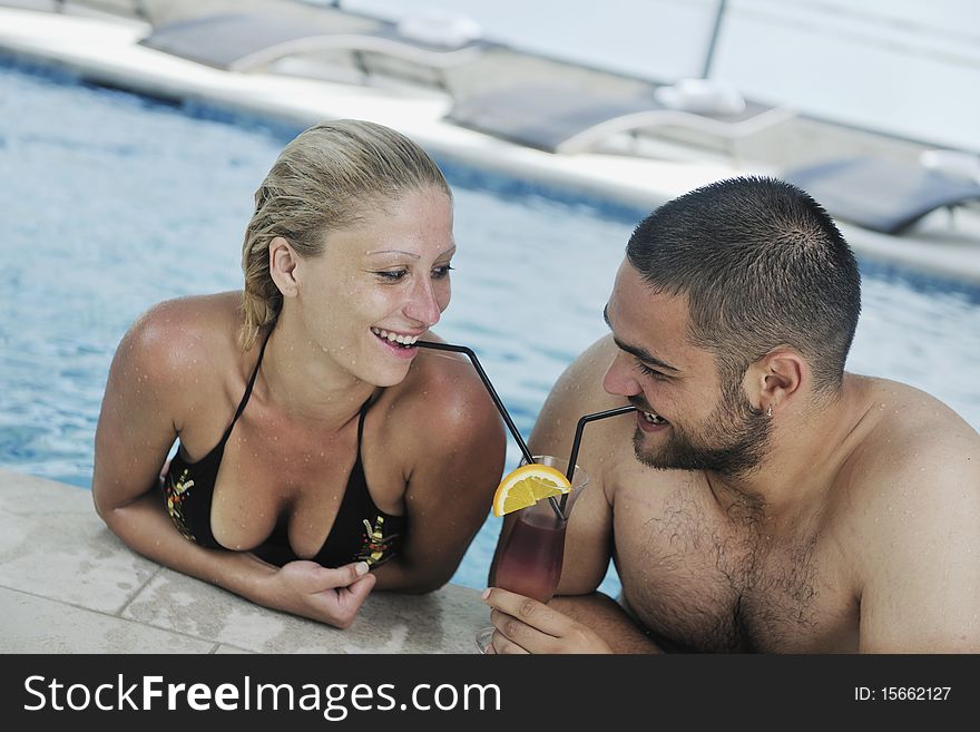 Happy young couple in love have fun relax and drink coctail at indoor wellness swimming pool. Happy young couple in love have fun relax and drink coctail at indoor wellness swimming pool