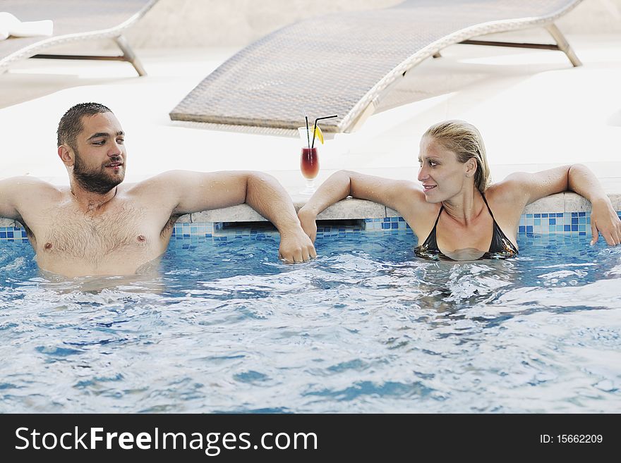 Happy young couple in love have fun relax and drink coctail at indoor wellness swimming pool. Happy young couple in love have fun relax and drink coctail at indoor wellness swimming pool