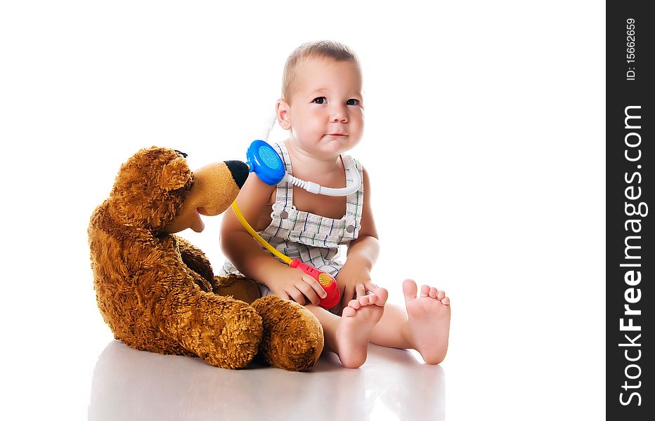 Little boy playing doctor with a teddy bear - studio shot - isolated