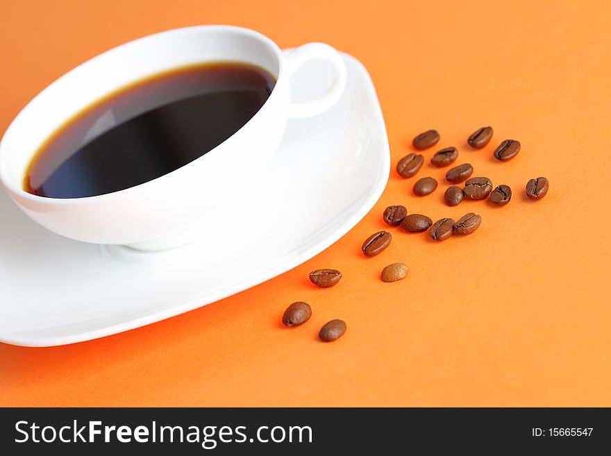 Coffee beans and cup of coffee on the orange background. Coffee beans and cup of coffee on the orange background