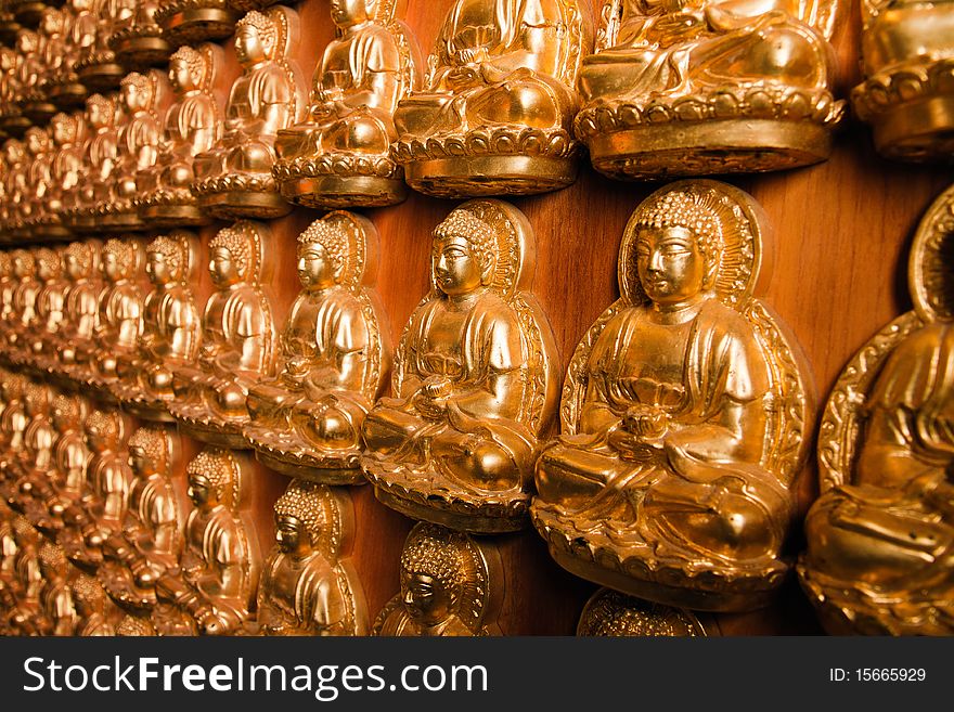 Many golden buddha image on wood wall