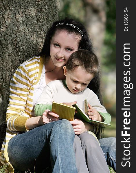 Mother and son reading book outdoors