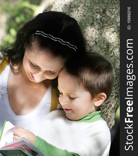 Mother and son reading book outdoors