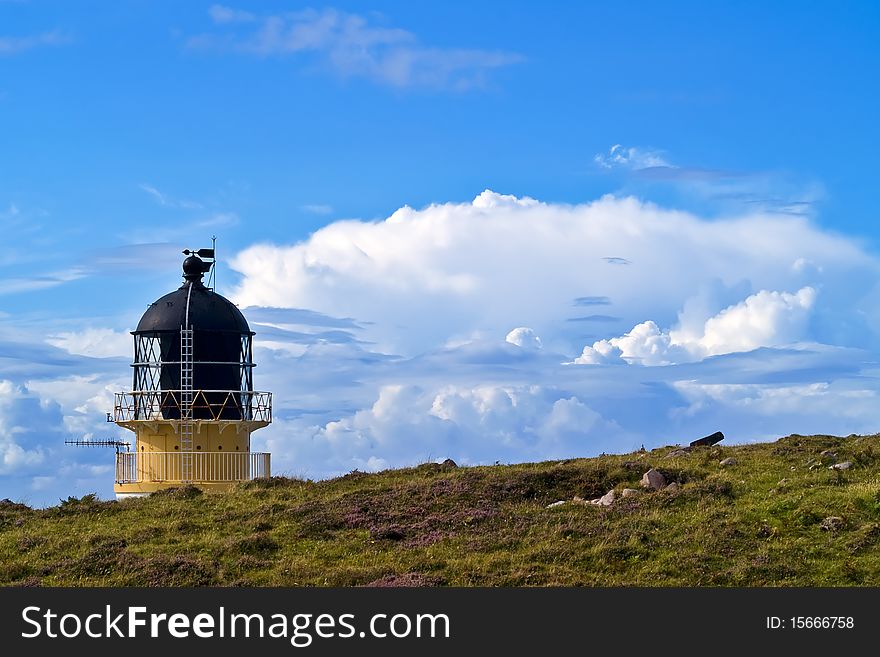 Rubha Reidh Lighthouse bhind a hill with coming storm clouds in the background. Rubha Reidh Lighthouse bhind a hill with coming storm clouds in the background