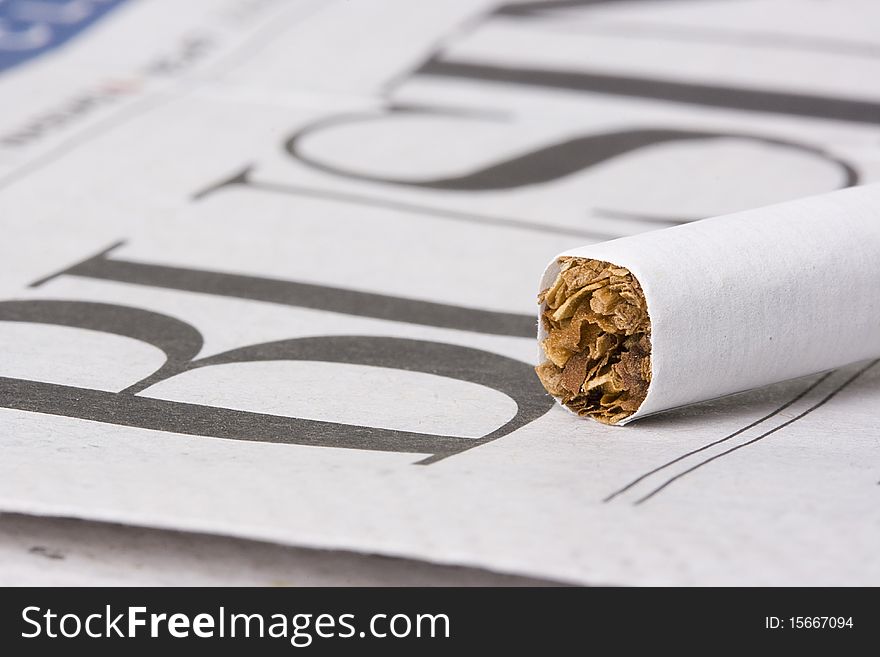 A cigarette laying on top of a newspaper with the word business on it. A cigarette laying on top of a newspaper with the word business on it.