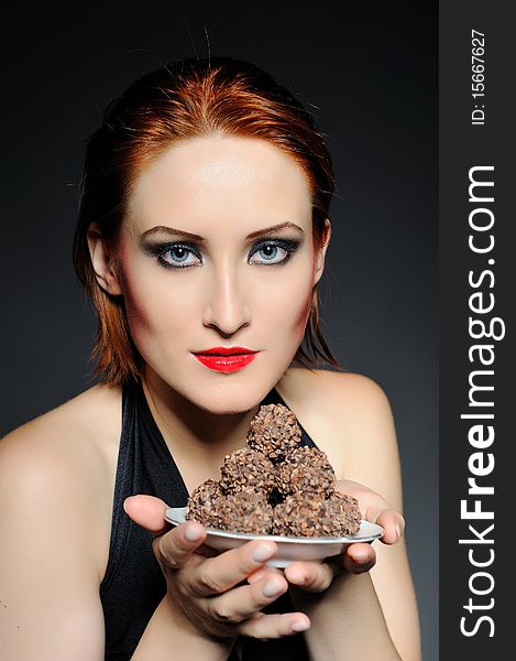 Beautiful retro woman with red lips holding many truffel chocolate sweets. focus on sweets. Beautiful retro woman with red lips holding many truffel chocolate sweets. focus on sweets